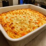 Close-up of a bubbly, golden-brown baked Buffalo chicken dip topped with melted cheese.