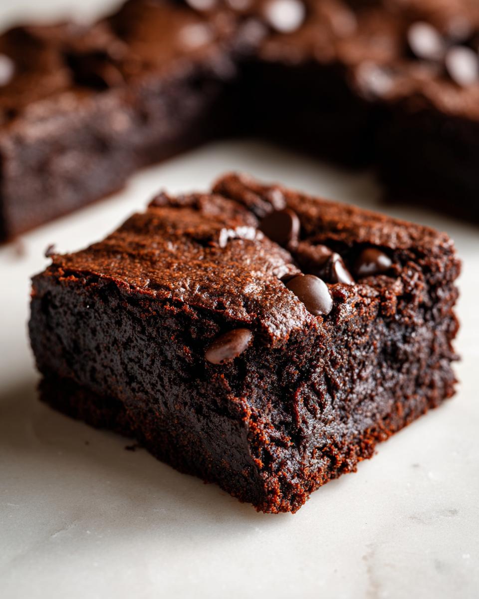 A close-up shot of a rich, fudgy square of sweet potato brownies topped with melted chocolate chips.