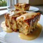 Close-up of a moist slice of bread pudding generously covered in creamy caramel sauce.
