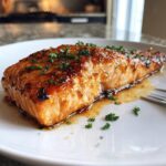 Close-up of a perfectly cooked honey garlic salmon fillet, glazed and garnished with fresh parsley.