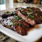 Close-up of perfectly cooked, sliced steak glistening with juices, seasoned with cilantro, prepared using a carne asada marinade.