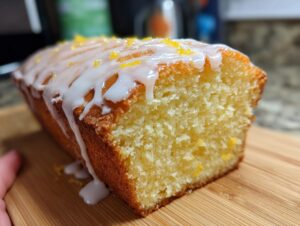 Close-up of a moist slice of lemon pound cake topped with white glaze and lemon zest.