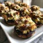 Close-up of baked sausage stuffed mushrooms topped with melted cheese and herbs, ready to serve.
