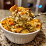 A spoonful of creamy Leftover turkey casserole, showing shredded turkey and carrots, lifted from a white ramekin.