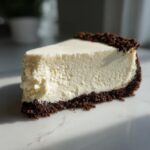 A perfect slice of creamy no bake cheesecake featuring a thick, white filling and a dark chocolate crumb crust.