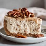A close-up of a thick slice of Pecan cream pie showing the creamy filling, crust, and whole pecans on top.