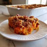 A close-up slice of rich orange southern sweet potato casserole topped with a crunchy pecan streusel.
