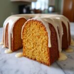 A slice cut from a bundt-shaped sweet potato pound cake covered in a thick, dripping vanilla glaze.