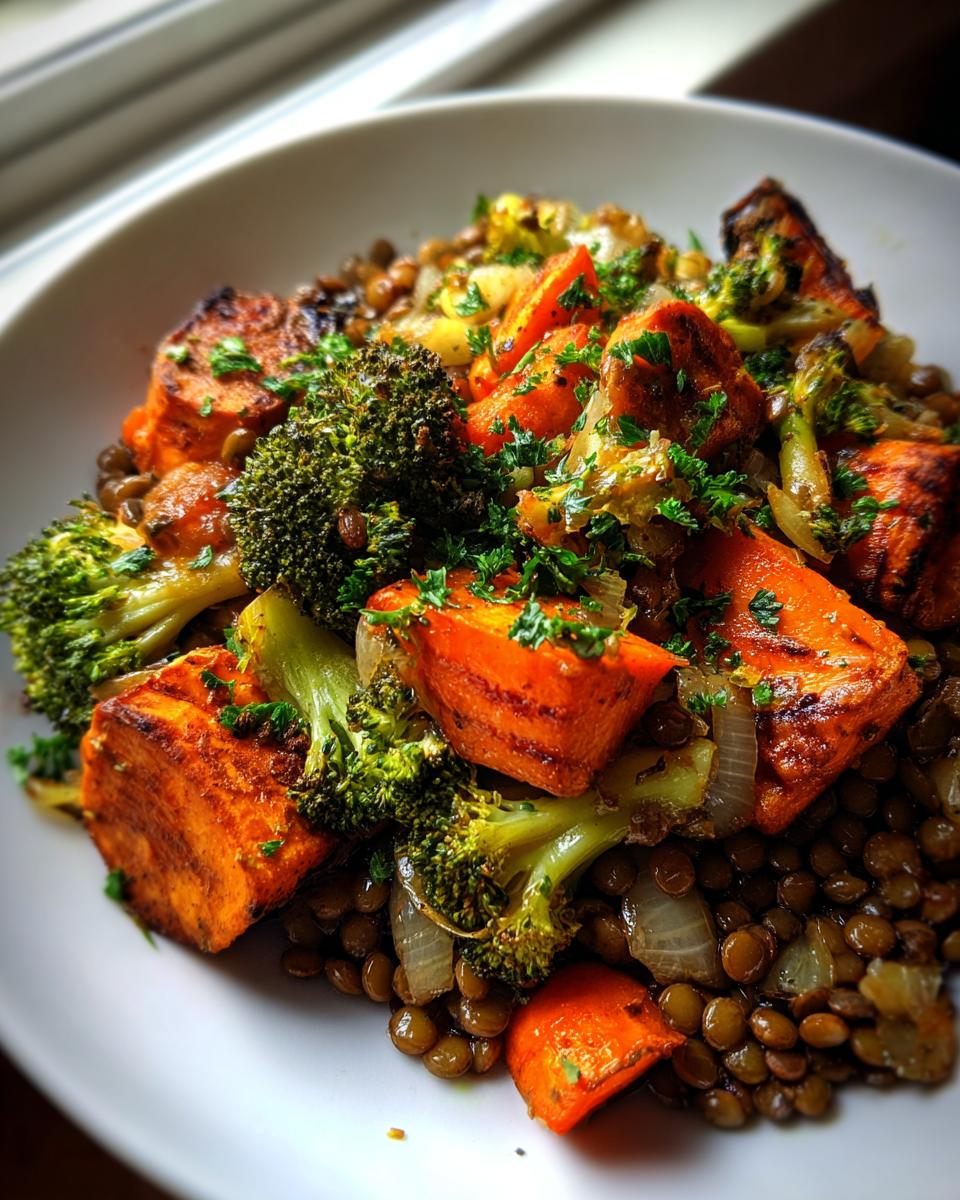 Close-up of a bowl featuring roasted sweet potatoes, broccoli, and onions served over brown lentils, part of a veggie lentil salad.