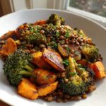 Close-up of a hearty veggie lentil salad featuring roasted sweet potatoes, charred broccoli florets, and brown lentils, topped with parsley.