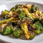 Close-up of crispy, charred roasted broccoli florets topped with grated Parmesan cheese.