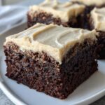 Close-up of a rich, dark square slice of banana bread brownies topped with thick, creamy frosting.