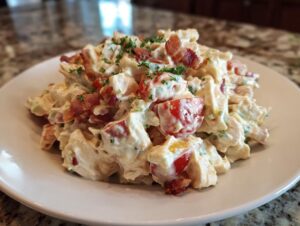 Close-up of a mound of creamy BLT chicken salad topped with crispy bacon bits and fresh parsley.