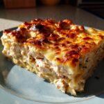 A thick slice of rich chicken alfredo lasagna featuring layers of shredded chicken and a bubbly, browned cheese topping.