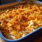 Close-up of a baked chicken noodle casserole with melted cheddar cheese and a crispy, golden breadcrumb topping.