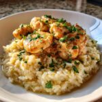 Close-up of tender chicken scampi pieces served over creamy garlic parmesan rice, garnished with fresh parsley.