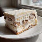 A close-up of a thick, layered slice of creamy Christmas tree cheesecake with visible nuts and chocolate pieces.