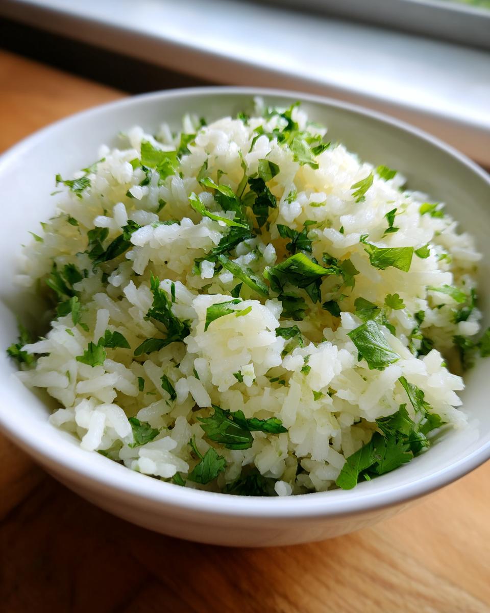A close-up of fluffy cilantro lime rice served in a white bowl, garnished with fresh green herbs.