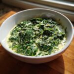 Close-up of rich, homemade creamed spinach recipe served hot in a white bowl.