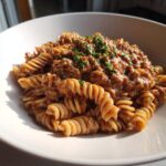 A close-up of creamy beef pasta made with fusilli noodles, topped with fresh parsley.