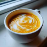 Close-up of bright orange butternut squash soup topped with a swirl of cream.