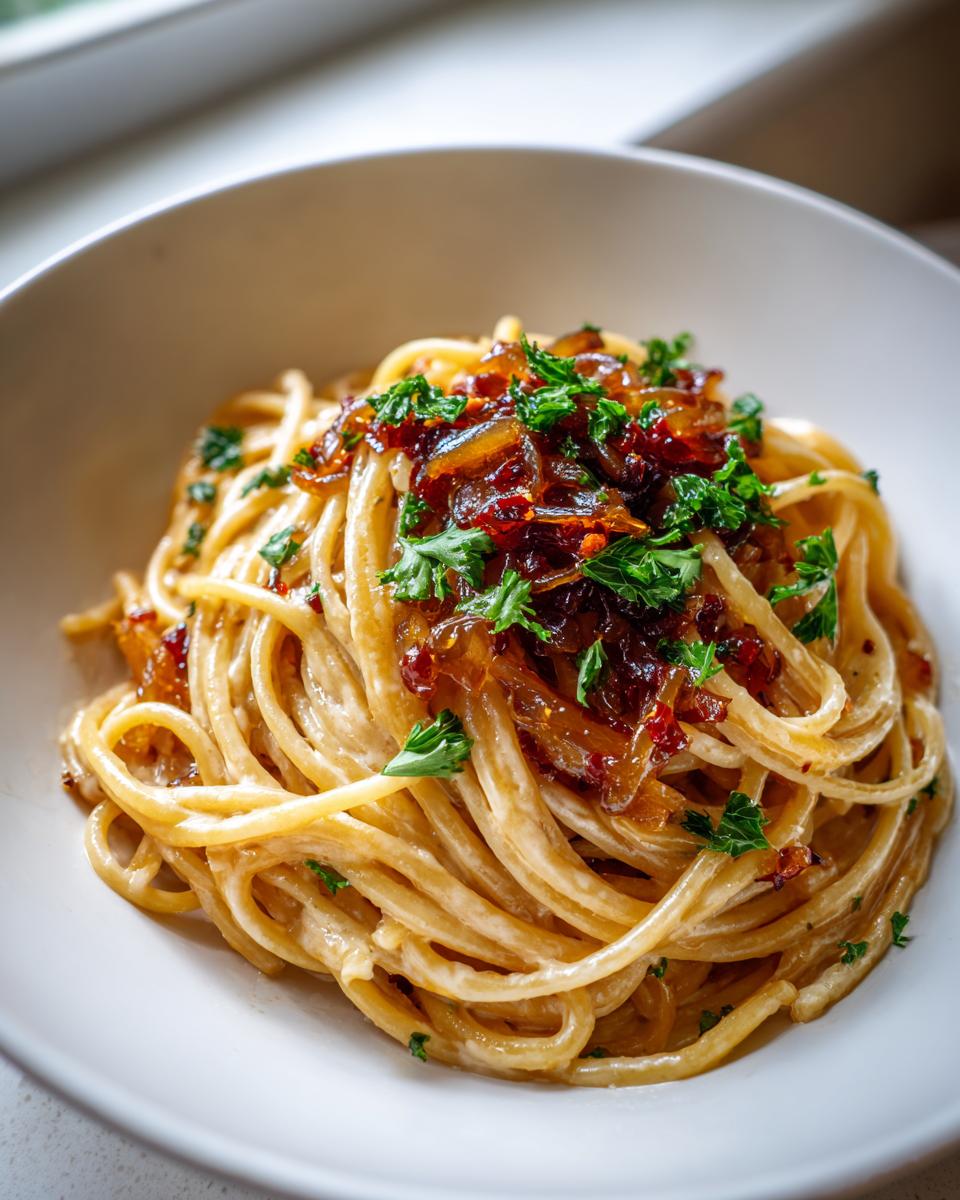 Close-up of creamy spaghetti topped with rich caramelized onion pasta and fresh parsley.