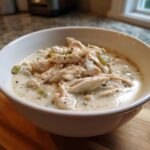 Close-up of a white bowl filled with creamy keto white chicken chili, featuring shredded chicken and green peppers.