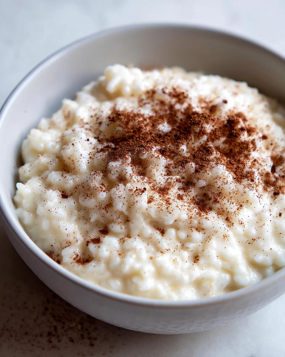 Close-up of a bowl of creamy rice pudding recipe generously sprinkled with ground cinnamon.