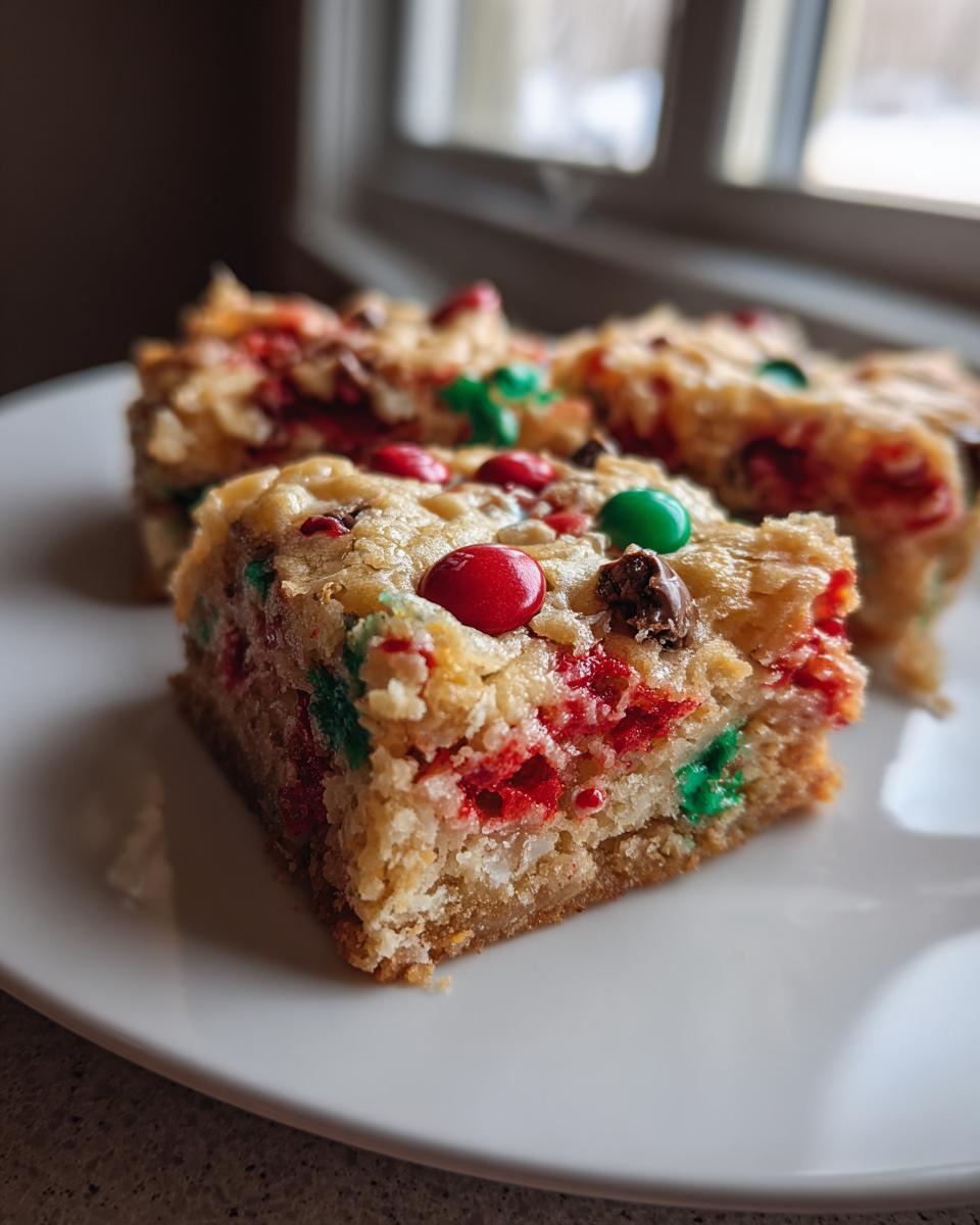 A close-up of three chewy christmas cookie bars topped with red and green candies on a white plate.