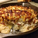 A scoop taken out of the French Onion Chicken Bake showing melted cheese, chicken, and creamy rice underneath a crispy topping.