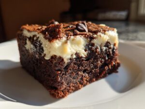 Close-up of a rich, dark gingerbread brownies square with a thick, creamy white swirl topping.