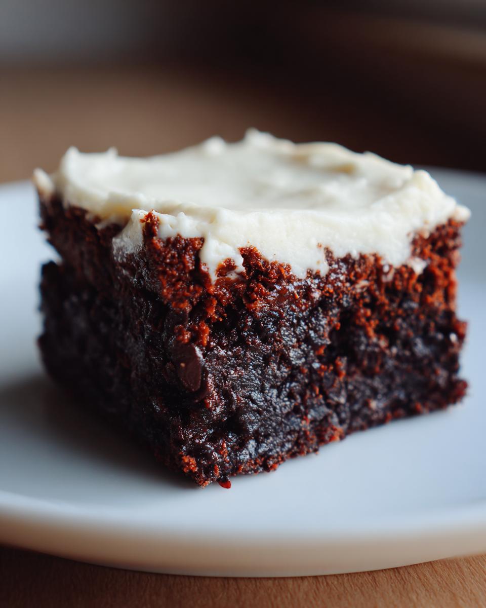 Close-up of a rich, dark gingerbread brownies square topped with thick white cream cheese frosting.