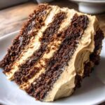 Close-up of a multi-layered slice of gingerbread latte cake showing dark brown cake layers and light tan coffee-flavored frosting.