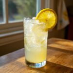 A tall glass filled with ice and homemade lemonade, garnished with a bright lemon slice.