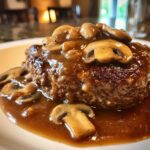 Close-up of a juicy salisbury steak smothered in rich brown mushroom gravy.