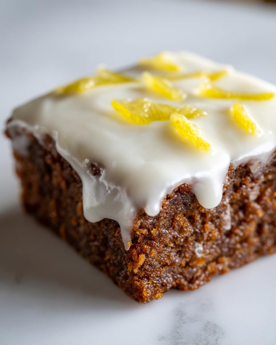 A close-up of a single, rich, dark-colored lemon brownies square topped with thick white glaze and lemon zest.