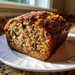 A close-up of a freshly baked slice of zucchini banana bread showing a moist crumb and dark crust.