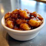 Close-up of thick, glossy apple pie filling with cinnamon spice served in a small white bowl.