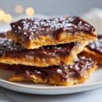 A stack of three rich saltine cracker toffee squares topped with melted chocolate and flaky sea salt.