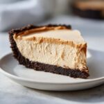 A close-up slice of no bake peanut butter pie with a thick, creamy filling and dark chocolate crust.