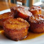 Close-up of thick, round slices of southern candied yams glistening with a rich, dark brown sugar glaze.