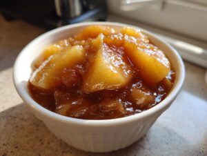 Close-up of thick, glossy, spiced apple pie filling served in a small white ramekin.