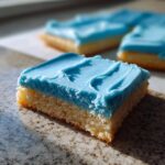 Close-up of a square sugar cookie bar with thick, bright blue sugar cookie icing that hardens.