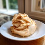 A beautiful swirl of homemade cinnamon butter dusted with extra cinnamon spice on a white plate.
