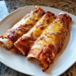 Three perfectly baked cheese enchiladas smothered in red sauce and melted cheddar and Monterey Jack cheese.