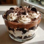 Layers of chocolate mousse, cream, and cookie crumbs topped with whipped cream and chocolate shavings in a Baileys Chocolate Cheesecake Trifle.