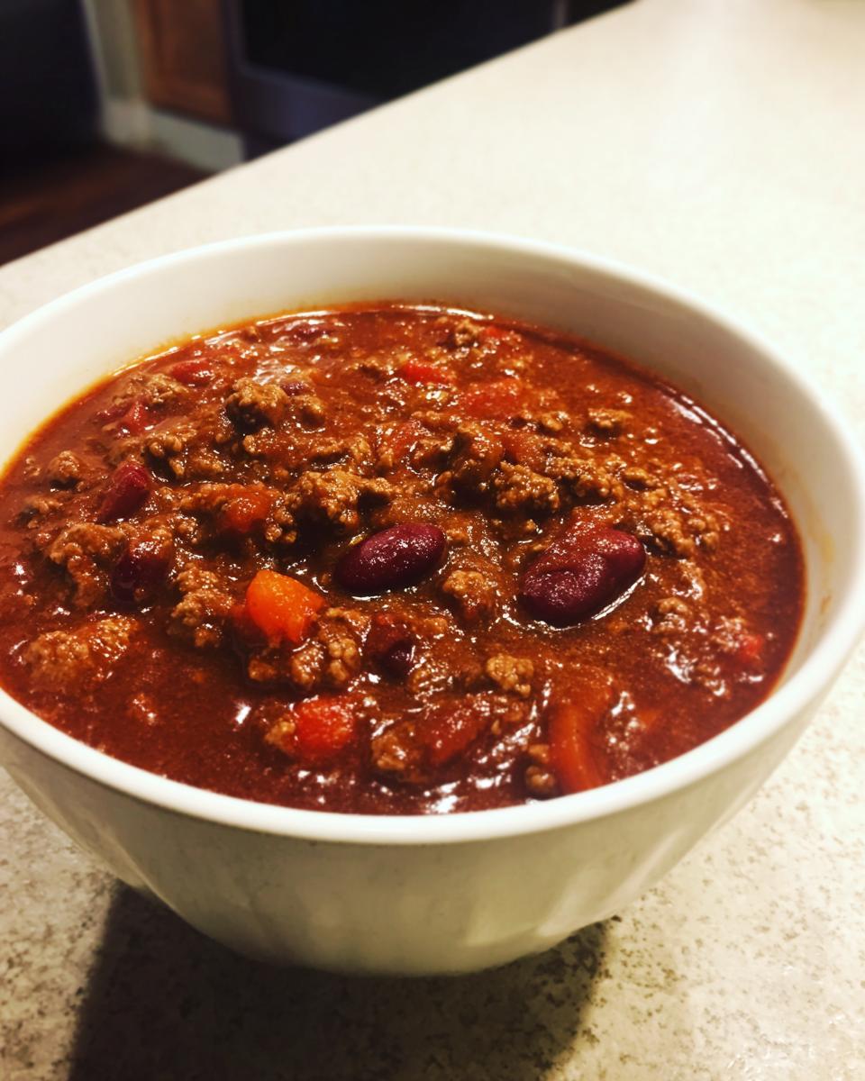 Close-up of a white bowl filled with rich, thick high protein chili featuring ground meat and kidney beans.