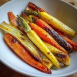 Close-up of vibrant, colorful roasted vegetables, primarily orange and yellow carrots, slightly charred.
