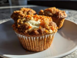 Close-up of a delicious carrot cake muffin with a cream cheese center and streusel topping.