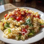 A close-up of creamy blt pasta salad featuring rotini pasta, crisp lettuce, cherry tomatoes, and crumbled bacon.